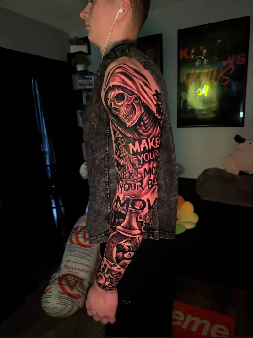 Detailed black and grey skull and lettering tattoo sleeve by Hasan Ink